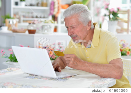 Emotional senior man posing and using laptop at home Emotional senior man posing and using laptop at home 64693096