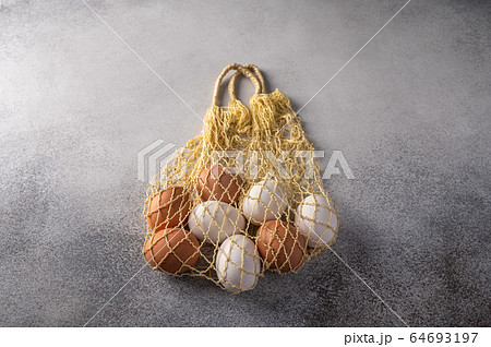 Brown and white chicken eggs in string bag on a light textured background. Copy space Brown and white chicken eggs in string bag on a light textured background. Copy space 64693197