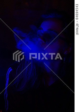 Close up portrait of vaping girl in neon blue light 64694543