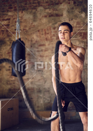 Young athlete man in training with ropes against background of brick wall, punching bag Young athlete man in training with ropes against background of brick wall, punching bag 64694610