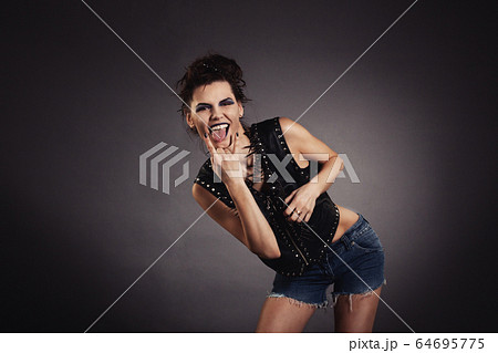 creative woman in black jacket and denim shorts showing gesture. Rocker style. 64695775