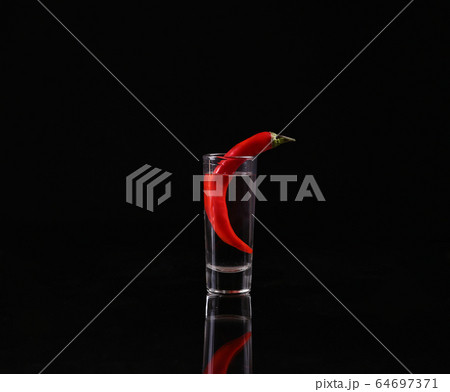Shot of vodka with chili peppers on a black Shot of vodka with chili peppers on a black 64697371