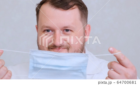 bearded male doctor is trying to put on a protective mask and get mad at her. Hygiene concept 64700681