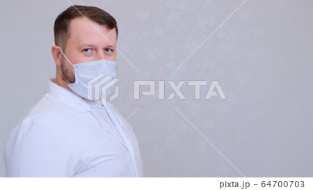 man in a protective mask and a white shirt looks at the camera, close-up. Hygiene concept. prevent man in a protective mask and a white shirt looks at the camera, close-up. Hygiene concept. prevent 64700703