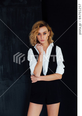 Portrait of a beautiful young fashionable blonde woman in a shirt and black shorts 64701257