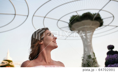 Girl on the background futuristic metal flowers in Dubai Miracle Garden Park. 64702001