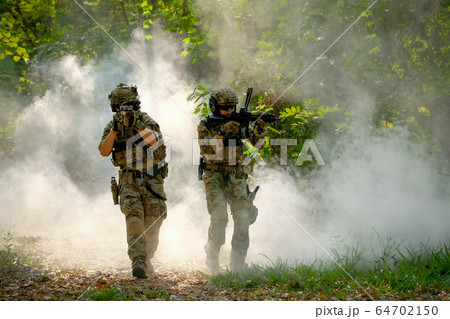 Two soldiers with the fighting uniform walk on the ground and point gun to enemy Two soldiers with the fighting uniform walk on the ground and point gun to enemy 64702150
