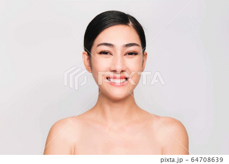 young beautiful asian woman with clean and bright skin, Cosmetic Beauty Concept,hands touch on the cheek, smiling and friendly face isolated on grey background 64708639