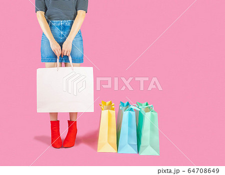 The woman low body part wore Denim skirt and red boots. Carrying a shopping bag in many pastel colors on pink background selective focus with copy space The woman low body part wore Denim skirt and red boots. Carrying a shopping bag in many pastel colors on pink background selective focus with copy space 64708649
