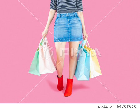 The woman low body part wore Denim skirt and red boots. Carrying a shopping bag in many pastel colors on pink background selective focus with copy space The woman low body part wore Denim skirt and red boots. Carrying a shopping bag in many pastel colors on pink background selective focus with copy space 64708650