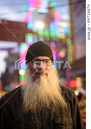 Mature bearded tourist man with eyeglasses in Chinatown at night 64714874