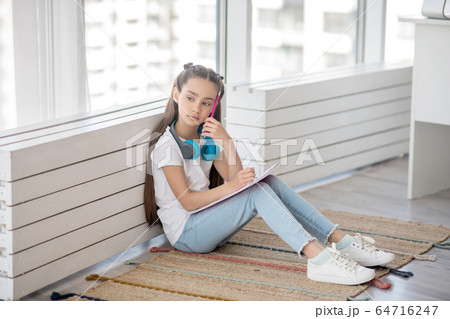 Long-haired girl in white tshirt sitting on the floor 64716247