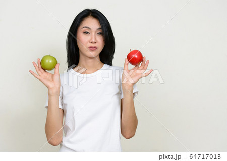 Portrait of young Asian woman choosing between two apples 64717013