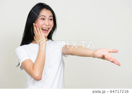 Portrait of happy young beautiful Asian woman looking surprised Portrait of happy young beautiful Asian woman looking surprised 64717216
