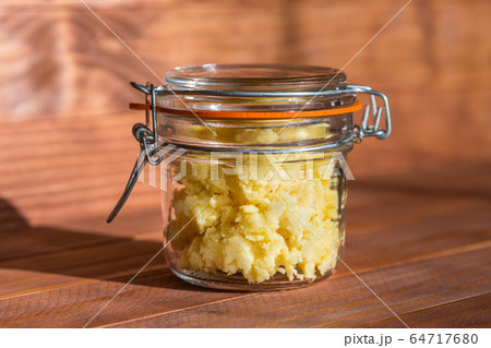 Cheese pate with garlic in a transparent jar on a wooden table at sunny kitchen. 64717680