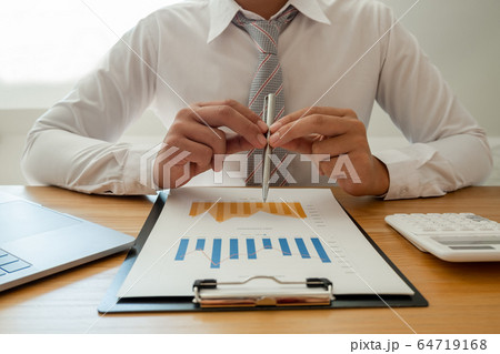 A business man is sitting at a desk and calculating financial graphs about real estate investment expenditures 64719168