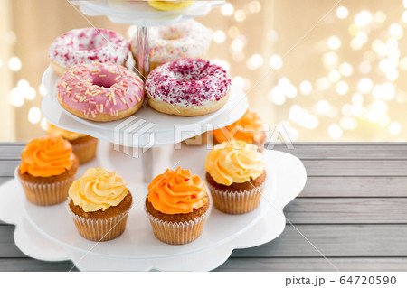 glazed donuts, cupcakes with frosting on stand glazed donuts, cupcakes with frosting on stand 64720590