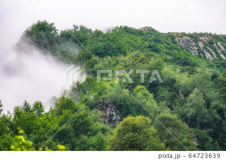 High mountain with green rocky slopes hidden in dense fog. High mountain with green rocky slopes hidden in dense fog. 64723639