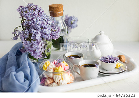 Breakfast with black tea or coffee and sweet meringue kisses on the white table. Breakfast with black tea or coffee and sweet meringue kisses on the white table. 64725223