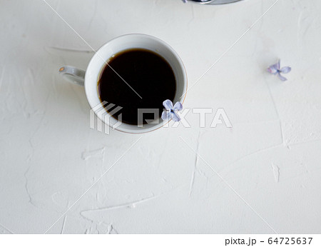 Black coffee or tea in the morning. Some fresh lilac flowers on the white table. Spring concept of breakfast. Black coffee or tea in the morning. Some fresh lilac flowers on the white table. Spring concept of breakfast. 64725637