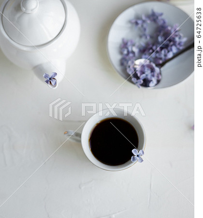 Black coffee or tea in the morning. Some fresh lilac flowers on the white table. Spring concept of breakfast. Black coffee or tea in the morning. Some fresh lilac flowers on the white table. Spring concept of breakfast. 64725638