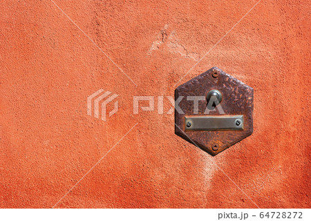 Old rusty doorbell on a red wall - Liguria Italy 64728272