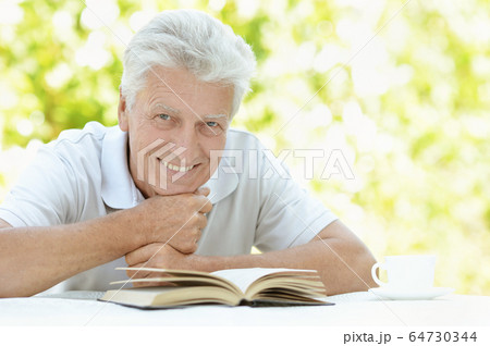 Portrait of senior man reading interesting book outdoors Portrait of senior man reading interesting book outdoors 64730344