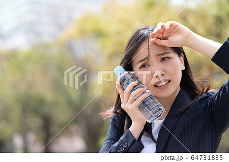 冷たいペットボトルを頬に当てる若い女性の写真素材 64731835 Pixta