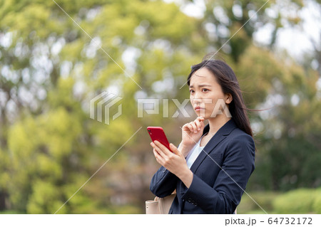 屋外でスマホを見て悩む若い女性 屋外でスマホを見て悩む若い女性 64732172