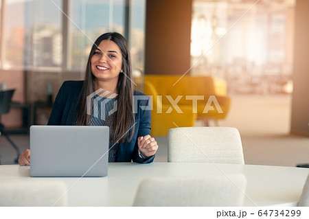 Smiling young business woman at work in modern office. 64734299