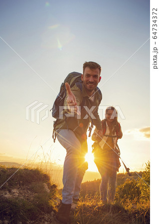 People helping each other hike up a mountain at sunrise. People helping each other hike up a mountain at sunrise. 64734372
