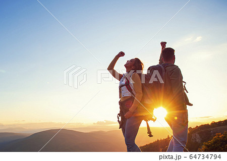 Couple on Top of a Mountain Shaking Raised Hands 64734794