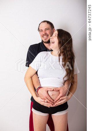 Cropped image of beautiful pregnant woman and her handsome husband hugging the tummy Cropped image of beautiful pregnant woman and her handsome husband hugging the tummy 64737245