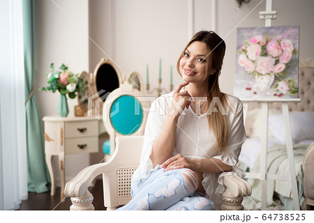 A woman artist with a picture on an easel at home. The painter paints oil paintings. A woman artist with a picture on an easel at home. The painter paints oil paintings. 64738525