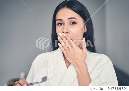 Stunned young Caucasian woman holding a toothbrush Stunned young Caucasian woman holding a toothbrush 64738970