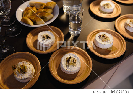 Many delicious hot baked camemberts with sultanas and rosemary on a table Many delicious hot baked camemberts with sultanas and rosemary on a table 64739557