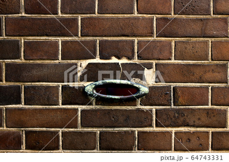 古いレンガ造りの壁に開けられたアンティークなデザインの郵便受けの投入口の写真素材