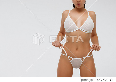 Woman in white lingerie holding laces of underwear Woman in white lingerie holding laces of underwear 64747131