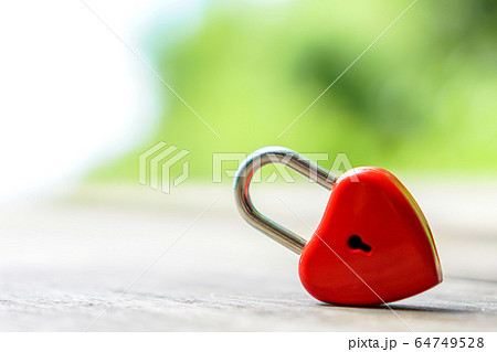 The red heart key is on a wooden table with a The red heart key is on a wooden table with a 64749528