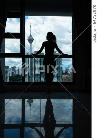 A slender girl is looking at the city through a A slender girl is looking at the city through a 64752970