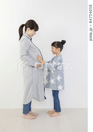妊娠中のお母さんのお腹を触る娘 64754056