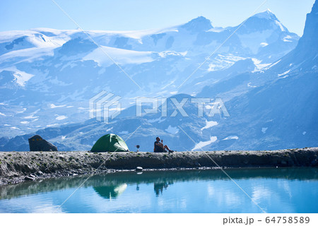 Man hiker resting by camp tent in mountains. Man hiker resting by camp tent in mountains. 64758589
