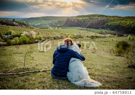 woman and dog enjoying outdoors on a green field 64758913