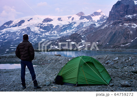 Man enjoying mountains scenery near tent. 64759272