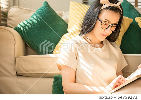 若い　女性　朝　本　読書　楽しむ　ソファー　屋内　人物　素材 64759273