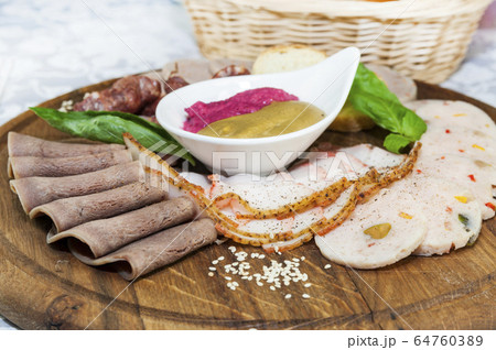 Wooden plate with several types of sausage and bacon sauce. 64760389