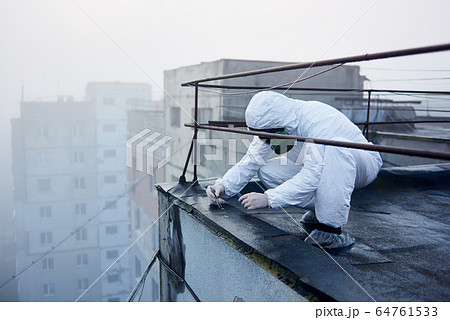 Worker scientist wearing protective coverall and gas mask doing ecological tests on the roof Worker scientist wearing protective coverall and gas mask doing ecological tests on the roof 64761533