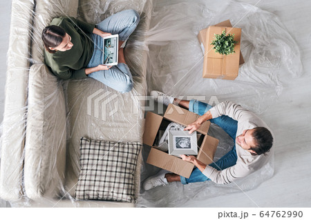 Top view of young woman with tablet chatting to husband with picture in frame 64762990