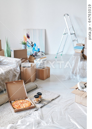 Open box with delivered appetizing pizza and two glasses of coffee on the floor 64763019