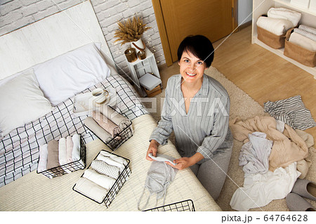 Beautiful young brunette woman folding things Beautiful young brunette woman folding things 64764628